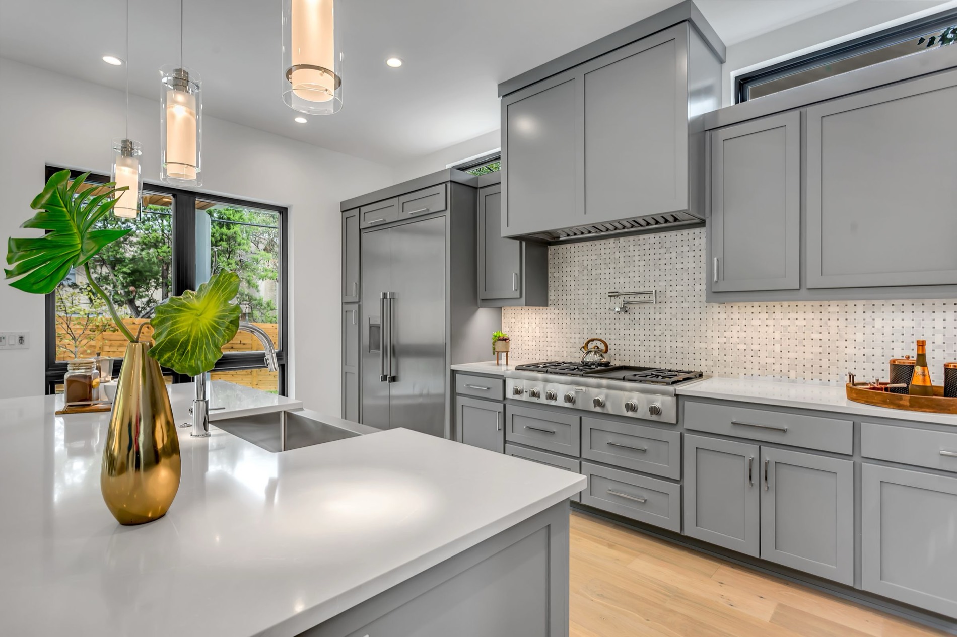 A painted shaker kitchen with an island, pendant lighting and stone worktops